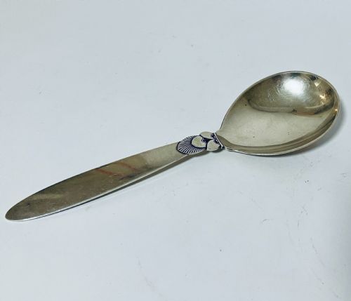 fig 1. A sterling silver serving spoon in the Georg Jensen Cactus pattern featuring a smooth oval bowl and a tapered handle with stylised leaf embellishments.