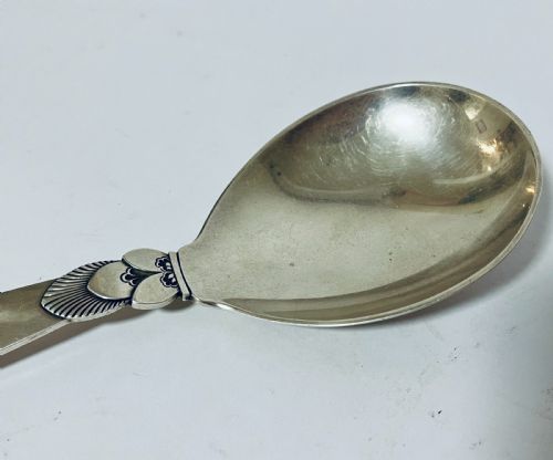 fig 2. A sterling silver serving spoon in the Georg Jensen Cactus pattern featuring a smooth oval bowl and a tapered handle with stylised leaf embellishments.