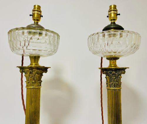 fig 2. A pair of brass Corinthian column table lamps featuring stepped square plinths, fluted columns, acanthus capitals, and cut glass reservoirs.