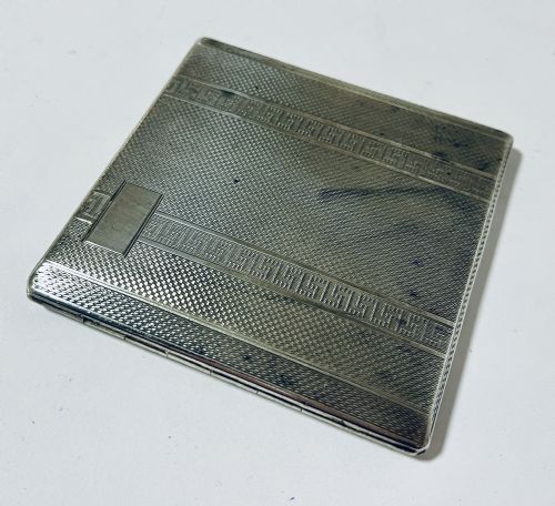 fig 1. An Art Deco silver rectangular cigarette case featuring engine-turned geometric patterning and a small rectangular vacant cartouche.