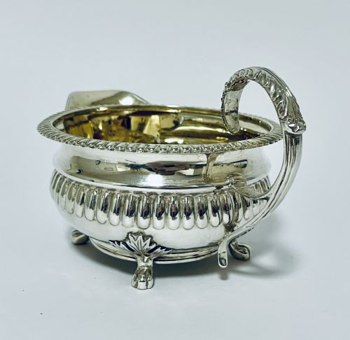 fig 1. A Georgian sterling silver milk jug featuring a fluted lower body, gadrooned rim, single scroll handle, and gilt interior.
