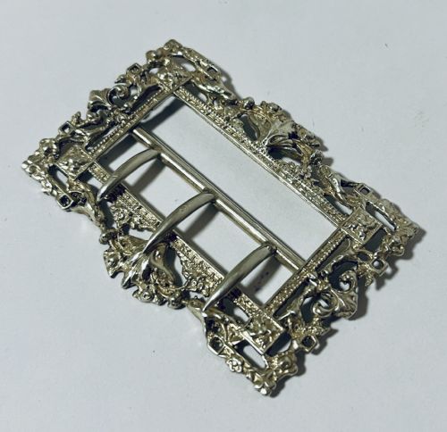 fig 1. A rectangular Victorian silver belt buckle featuring intricate openwork foliate motifs and three central fastening prongs.
