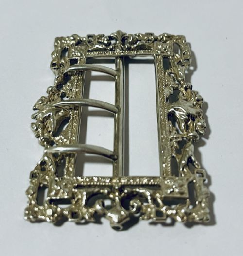 fig 2. A rectangular Victorian silver belt buckle featuring intricate openwork foliate motifs and three central fastening prongs.