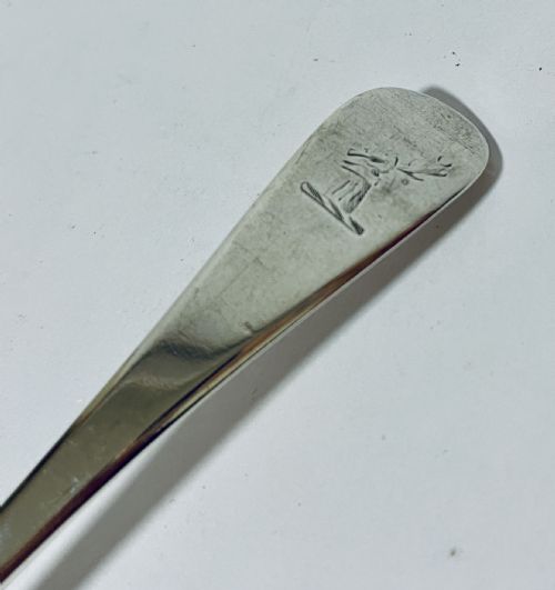 fig 1. An 18th-century sterling silver serving spoon featuring a plain oval bowl and an engraved heraldic crest on the flat handle terminal.