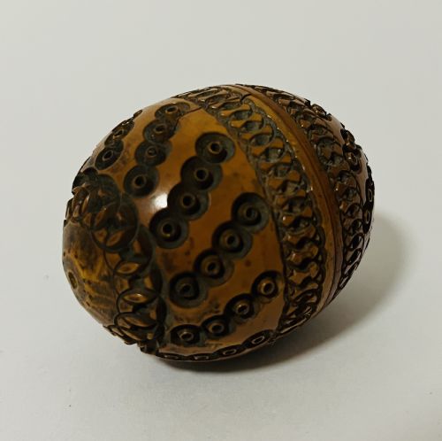 fig 1. An egg-shaped Victorian pomander carved from warm brown coquilla nut with geometric circular pierced patterns.