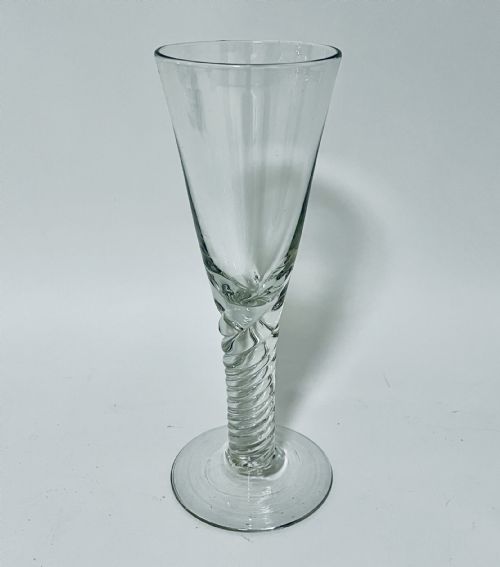 fig 1. A tall clear hand-blown glass featuring a conical funnel-shaped bowl, a twisted wrythen stem, and a flat circular foot.