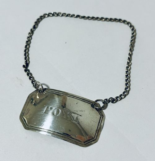 fig 1. A curved rectangular Georgian silver decanter label engraved with the word PORT, attached to a silver suspension chain.