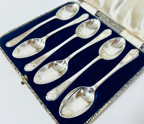 fig 2. A set of six silver teaspoons with crossed golf club motifs on the handles, arranged inside an open satin and velvet lined presentation case.