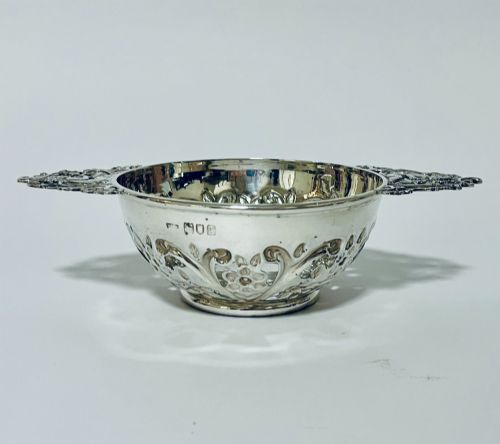fig 1. An Edwardian sterling silver quaich featuring intricate pierced floral sides, two ornate cast scroll handles, and hallmarks visible on the bowl.