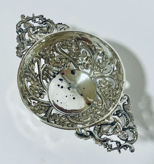 fig 2. An Edwardian sterling silver quaich featuring intricate pierced floral sides, two ornate cast scroll handles, and hallmarks visible on the bowl.