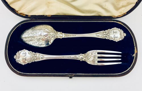 fig 1. An antique Victorian silver christening spoon and fork with intricate foliate engraving, arranged inside a velvet-lined dark leather presentation case.