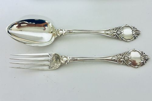 fig 2. An antique Victorian silver christening spoon and fork with intricate foliate engraving, arranged inside a velvet-lined dark leather presentation case.