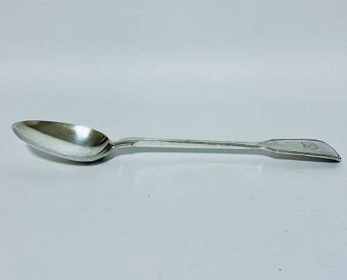 fig 1. A Victorian silver serving spoon displaying a fiddle pattern handle with an engraved crest on the terminal.