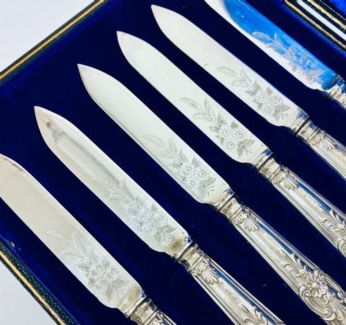 fig 3. A cased set of six silver-handled fruit knives with floral engraved blades, displayed inside a blue velvet-lined presentation box.