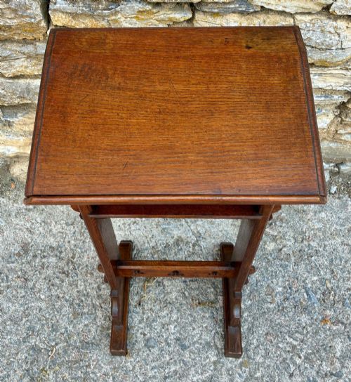 fig 1. A small antique dark oak church lectern featuring a slanted reading top, trefoil cutouts, and a trestle base.