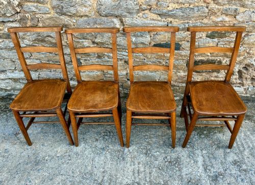 fig 1. A set of four matching antique wooden chapel chairs with contoured seats and ladder-back rails.