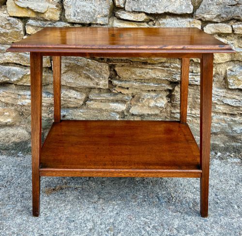 fig 1. An Arts and Crafts solid oak side table featuring a lower shelf, straight square legs, and dark circular wood inlays arranged in a grid pattern on the top surface.