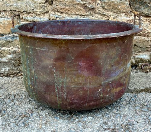 fig 1. A large, circular antique copper wash tub featuring twin wrought iron carrying handles, a rolled rim, and heavy surface oxidisation with verdigris.