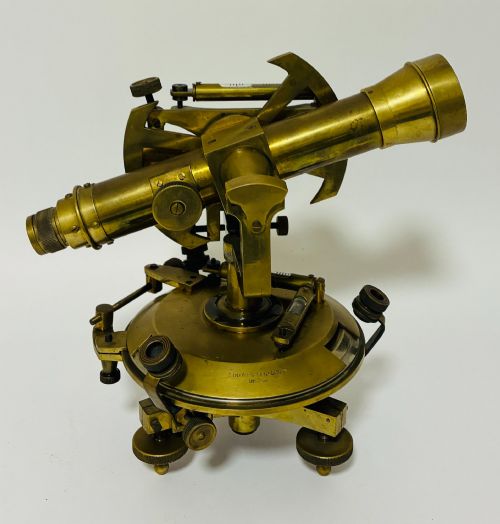 fig 1. An antique brass surveyors theodolite featuring a central sighting telescope, spirit levels, and knurled adjustment screws on a circular base.