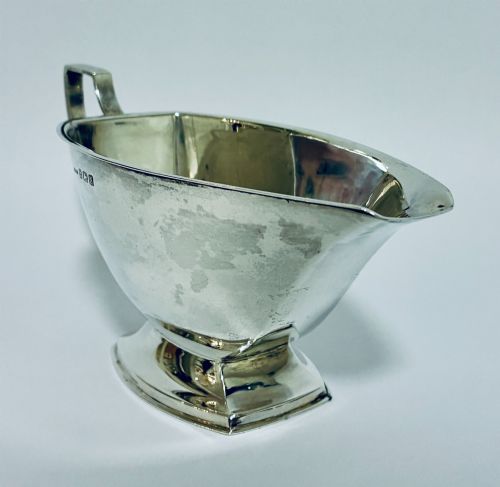 fig 1. An Art Deco sterling silver sauce boat featuring an angular handle, stepped pedestal base, and clear English hallmarks on the side.