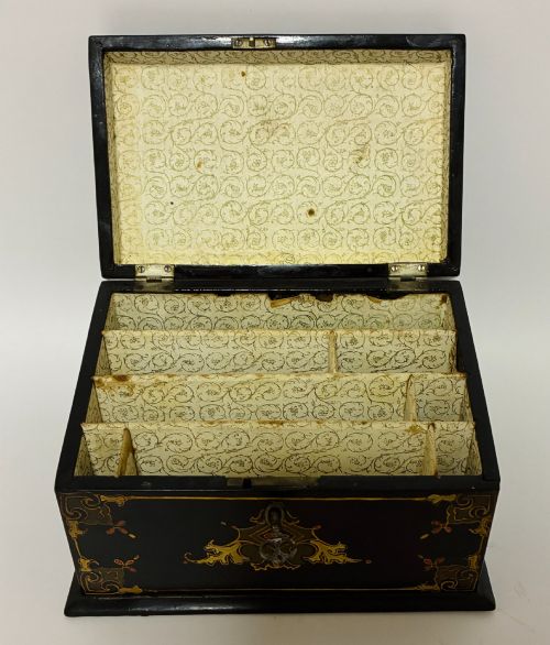 fig 1. A black lacquered Victorian papier-mache stationery box featuring mother-of-pearl flower inlays on the lid and gilded corner scrollwork around a central brass keyhole.