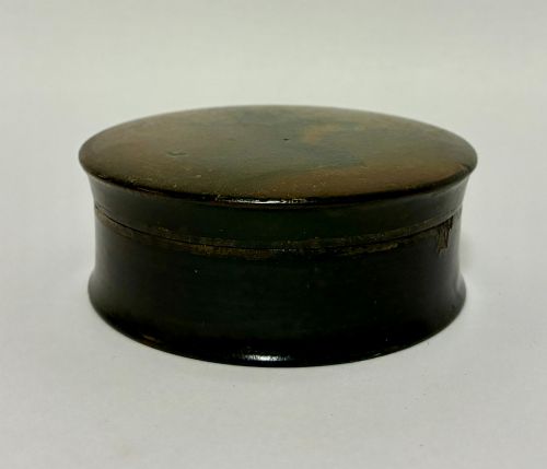 fig 2. A circular Georgian papier-mache table snuff box featuring a hand-painted depiction of a gentleman in a top hat and tailcoat against a dark lacquered background.