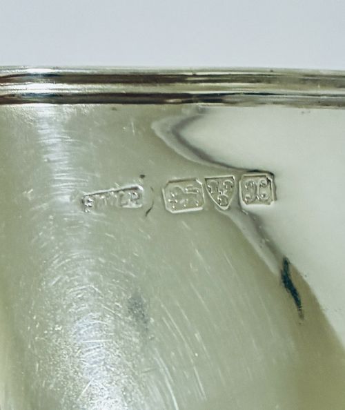 fig 2. A sterling silver helmet-shaped cream jug featuring a high loop handle, side hallmarks, and a square plinth base.