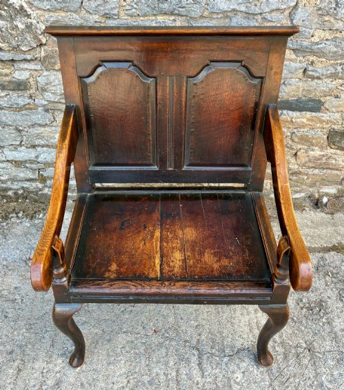 fig 2. An 18th-century Georgian dark oak settle featuring a twin arched-panel back, contoured armrests, and cabriole front legs.