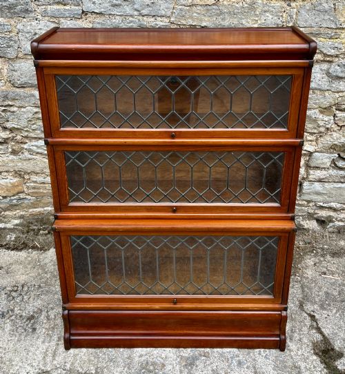 fig 1. A three-tier Globe Wernicke mahogany barristers bookcase featuring leaded glass lift-up doors and a moulded plinth base.