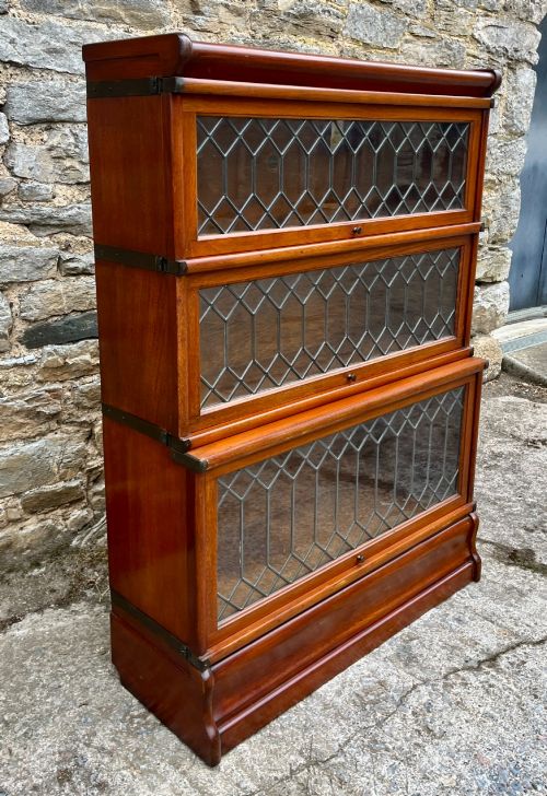 fig 2. A three-tier Globe Wernicke mahogany barristers bookcase featuring leaded glass lift-up doors and a moulded plinth base.