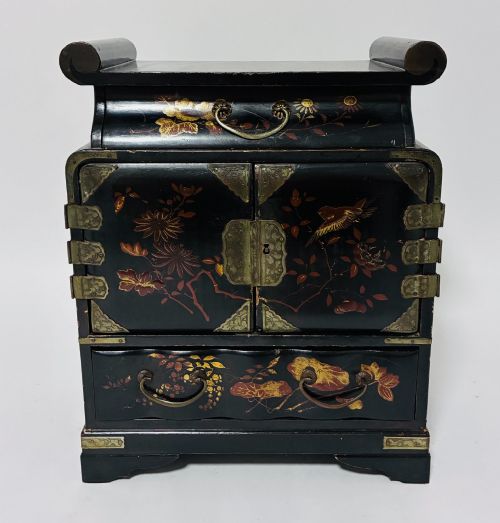 fig 1. A black lacquered Japanese tabletop cabinet featuring hand-painted botanical motifs and decorative engraved brass corner mounts.