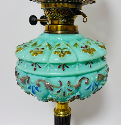 fig 1. A Victorian oil lamp featuring an etched frosted glass shade, a turquoise enamelled font, and a brass column on a dark stepped base.