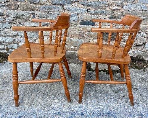 fig 2. A pair of antique wooden captains chairs with contoured elm seats, turned spindles, rounded armrests, and turned legs.