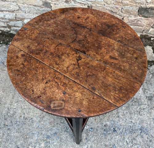 fig 1. An antique Georgian dark oak cricket table featuring a circular planked top resting on three straight legs with a lower triangular shelf.