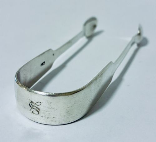 fig 1. A pair of plain polished sterling silver sugar tongs with spoon-shaped grips and assay hallmarks stamped along the inner curve.