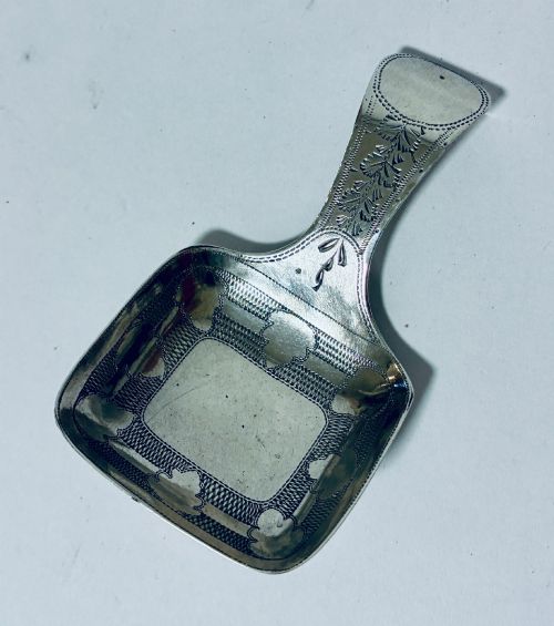 fig 1. A Georgian sterling silver caddy spoon with a rectangular shovel-form bowl and bright-cut engraved geometric patterns on the handle.