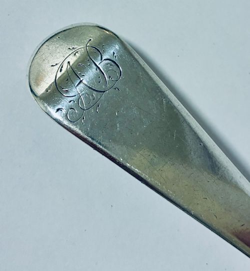 fig 1. An antique sterling silver serving spoon featuring a tapered handle with monogram engraving and an oval bowl.