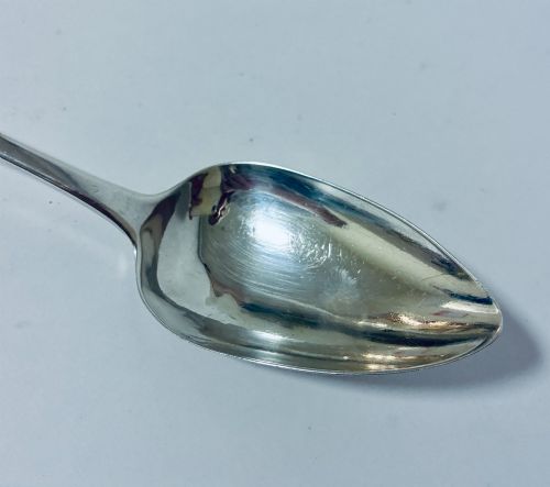 fig 2. An antique sterling silver serving spoon featuring a tapered handle with monogram engraving and an oval bowl.