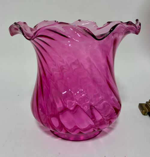 fig 2. A Victorian oil lamp featuring a swirl optique cranberry glass shade and reservoir set atop a brass column and relief-moulded square base.