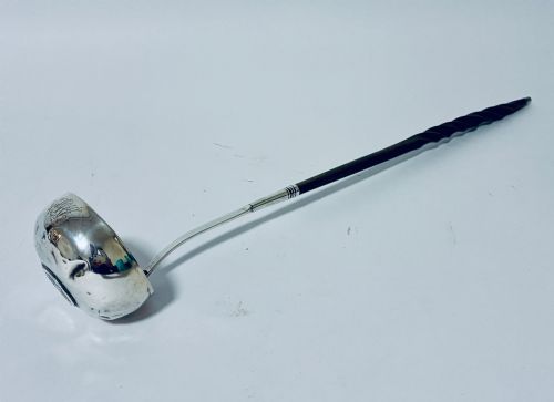 fig 1. An antique Georgian silver toddy ladle featuring a deep circular silver bowl attached to a long, dark twisted handle.