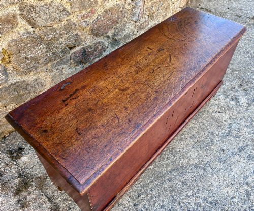 fig 2. A long early 18th-century oak sword chest featuring a hinged lid, hand-carved initials H R, the date 1724 on the front panel, and a central iron escutcheon.