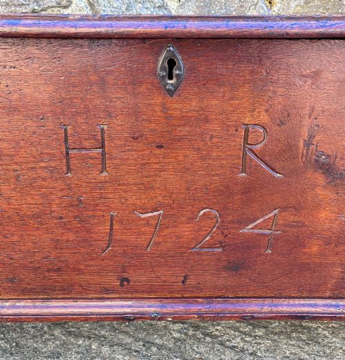 fig 3. A long early 18th-century oak sword chest featuring a hinged lid, hand-carved initials H R, the date 1724 on the front panel, and a central iron escutcheon.