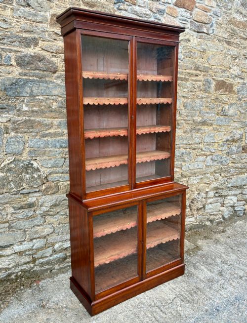 fig 1. A tall Victorian mahogany cabinet featuring an upper two-door glazed section with scalloped shelf edging set above a lower matching glazed cupboard.