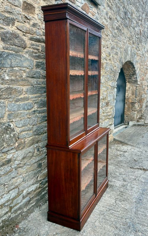 fig 2. A tall Victorian mahogany cabinet featuring an upper two-door glazed section with scalloped shelf edging set above a lower matching glazed cupboard.