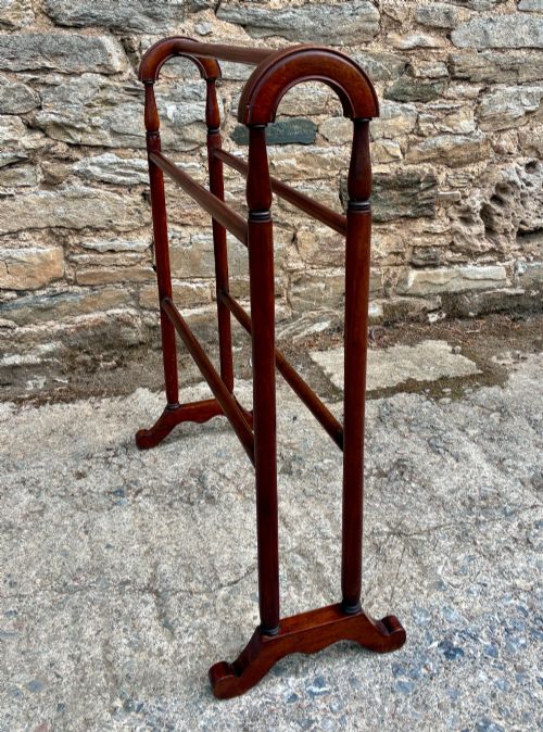 fig 1. A freestanding Victorian mahogany towel rail featuring arched top cresting, turned upright supports, four horizontal bars, and shaped trestle feet.