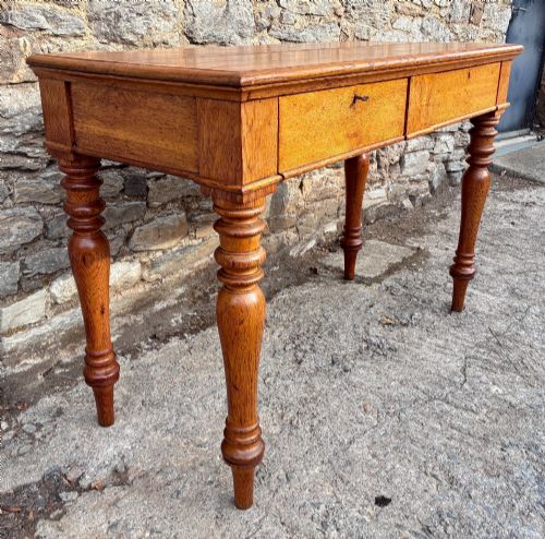 fig 2. A Victorian golden oak console table featuring a rectangular top with a moulded edge, two frieze drawers, and four turned legs.