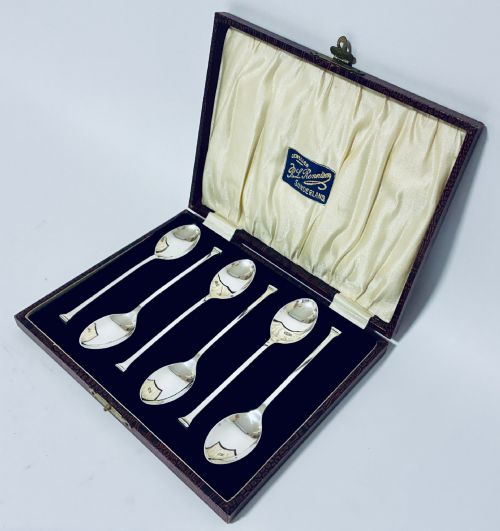 fig 1. A set of six silver seal top spoons displayed inside a dark presentation box lined with cream satin and navy velvet.