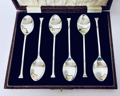 fig 2. A set of six silver seal top spoons displayed inside a dark presentation box lined with cream satin and navy velvet.