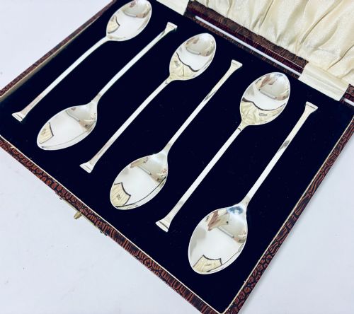 fig 3. A set of six silver seal top spoons displayed inside a dark presentation box lined with cream satin and navy velvet.