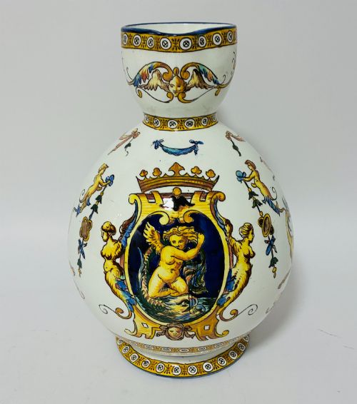 fig 1. A white tin-glazed earthenware ewer decorated with hand-painted Renaissance grotesque figures, a central crest, and a blue handle.
